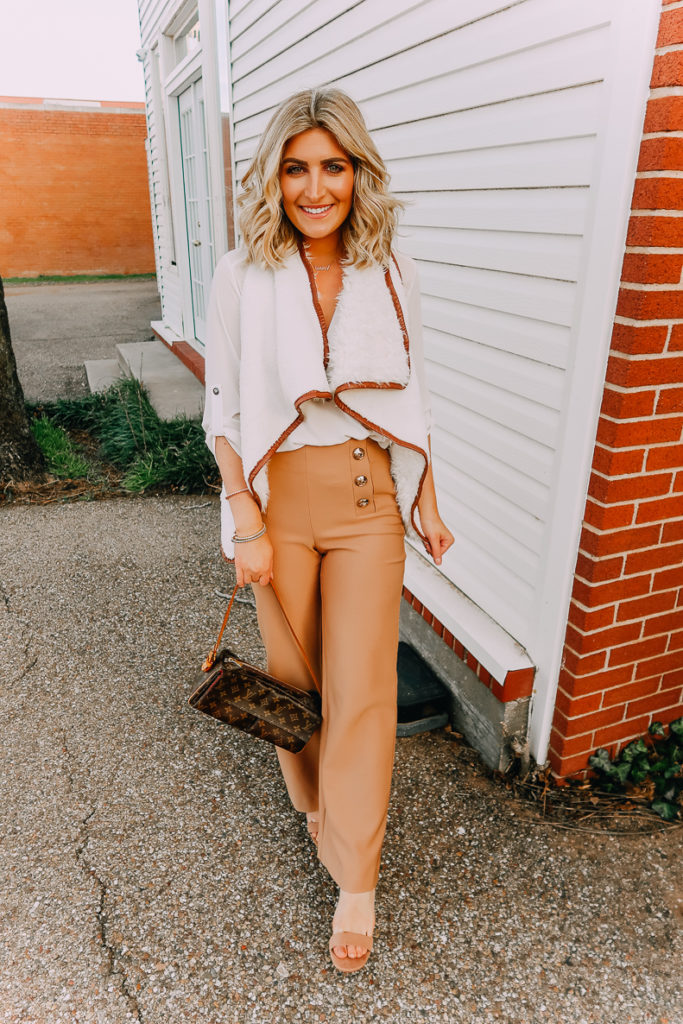 Ways To Wear a White Blouse featured by top US fashion blogger Audrey Madison Stowe; Image of woman wearing white blouse, shearling vest, work pants and nude heels.