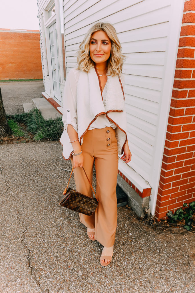 Ways To Wear a White Blouse featured by top US fashion blogger Audrey Madison Stowe; Image of woman wearing white blouse, shearling vest, work pants and nude heels.