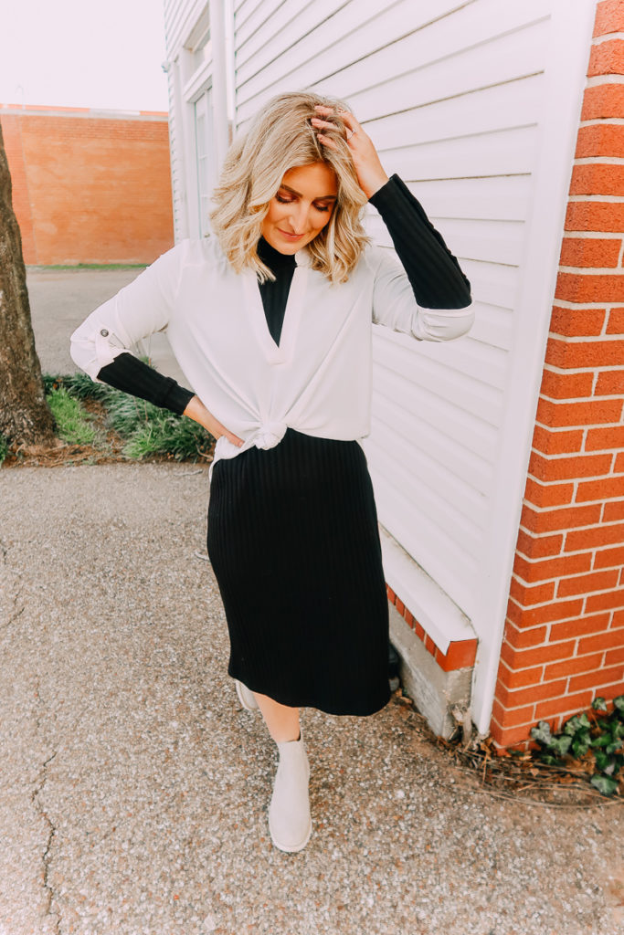 Ways To Wear a White Blouse featured by top US fashion blogger Audrey Madison Stowe; Image of woman wearing white blouse and black midi sweater dress.